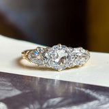 Antique Victorian three-stone with cushion-cut and pear-cut diamonds ring on a vintage book with a blurred background
