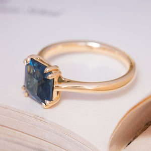 A vintage-inspired blue square-cut sapphire solitaire ring in yellow gold.
