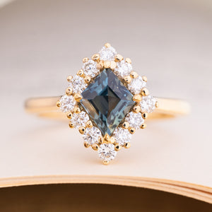 An antique-inspired, teal kite-cut sapphire and diamond cluster engagement ring in 14ct yellow gold.