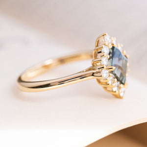 An antique-inspired, green kite-cut sapphire and diamond cluster engagement ring.