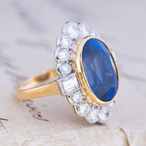Three-quarter view of a vintage natural sapphire and diamond halo cluster ring in yellow gold and platinum.
