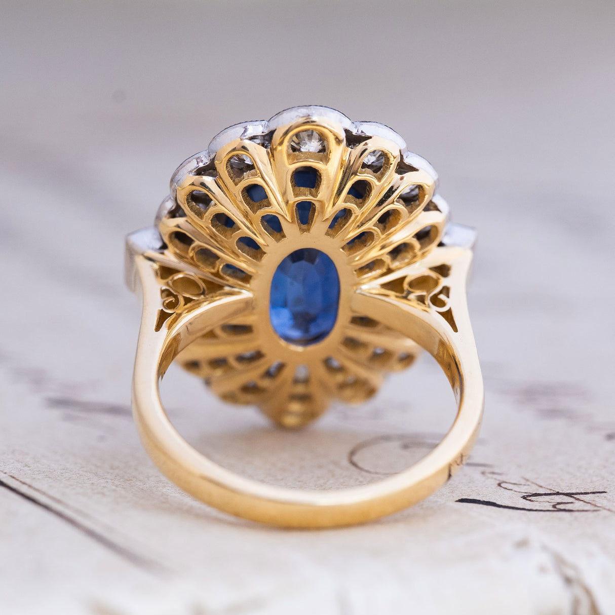 Gallery view of a vintage natural blue sapphire and diamond halo cluster ring showing the open basket setting in yellow gold and platinum.