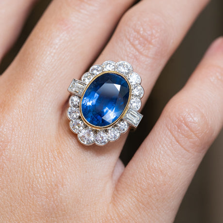 A vintage natural blue sapphire and diamond halo cluster ring worn on the finger.