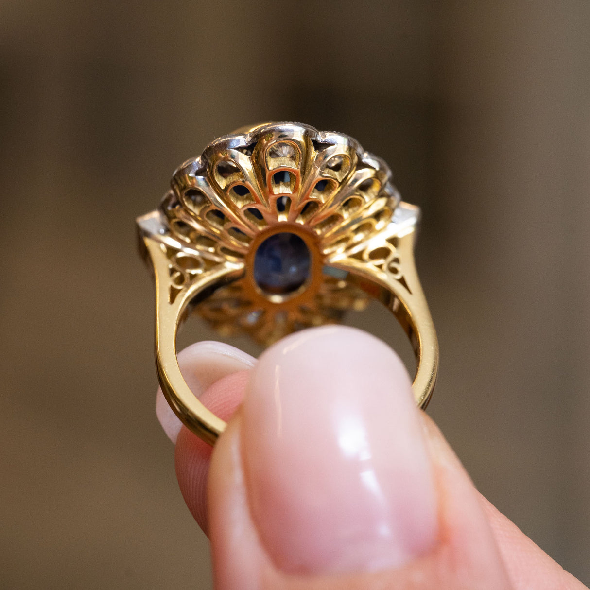 Rear view of a vintage natural sapphire and diamond halo cluster ring showcasing the intricate open gallery.