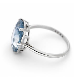 A solitaire sapphire platinum ring against a white background, seen from the side profile.