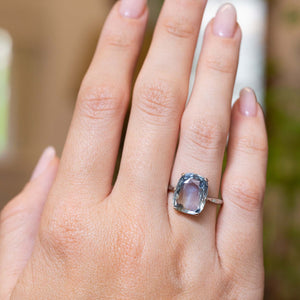 The sapphire solitaire ring worn on the finger, hand showed at a distance to display proportions of the ring.