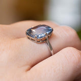 A sapphire platinum ring worn on the finger shown up close and from the side to show the low profile of the ring. 