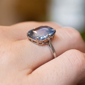 A sapphire platinum ring worn on the finger shown up close and from the side to show the low profile of the ring. 