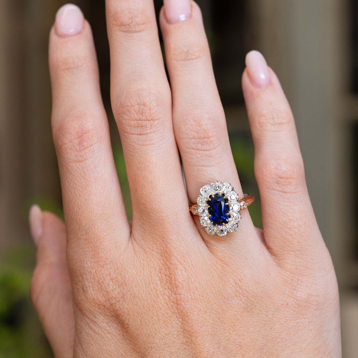 An antique Jugendstil royal-blue sapphire and diamond cluster ring worn on the hand.