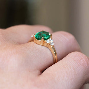 Side detail of a vintage-inspired oval-cut emerald and diamond engagement ring in yellow gold.