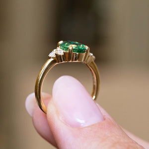 Gallery detail of a vintage-inspired oval-cut emerald and diamond trefoil engagement ring in yellow gold.