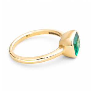 A vintage-inspired yellow gold solitaire engagement ring with an emerald at the centre.