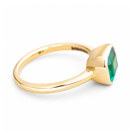 A vintage-inspired yellow gold solitaire engagement ring with an emerald at the centre.