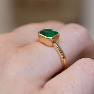 Side detail of an antique-inspired emerald-cut emerald solitaire engagement ring in 14ct yellow gold.