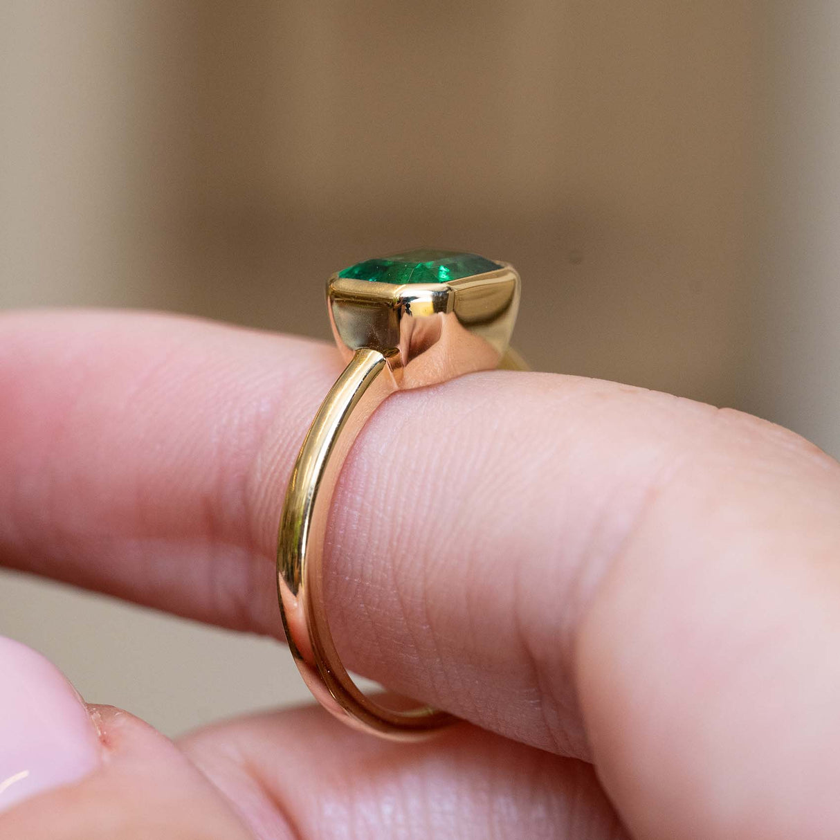 Gallery detail of an antique-inspired emerald-cut emerald solitaire engagement ring in 14ct yellow gold.