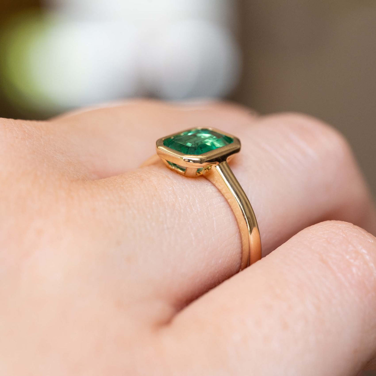 Side view of an antique-inspired emerald-cut emerald solitaire ring crafted in yellow gold.