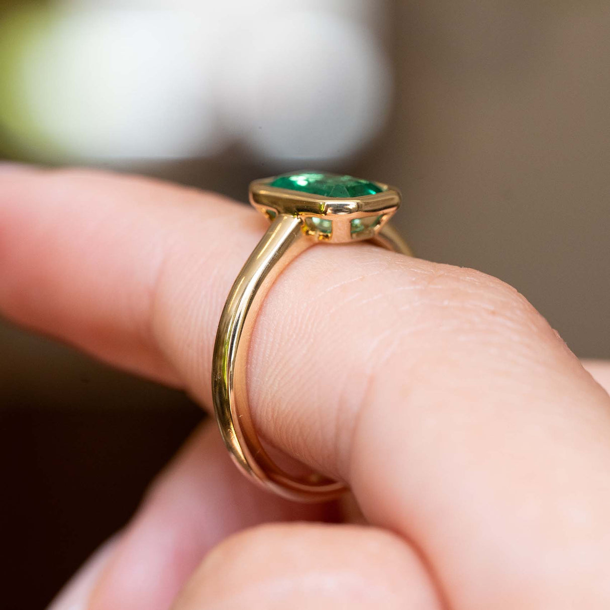 Gallery view highlighting the antique-inspired yellow gold setting of an emerald-cut emerald solitaire ring.