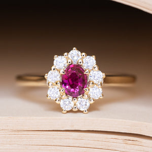 An antique-inspired pink ruby and diamond cluster engagement ring in yellow gold.