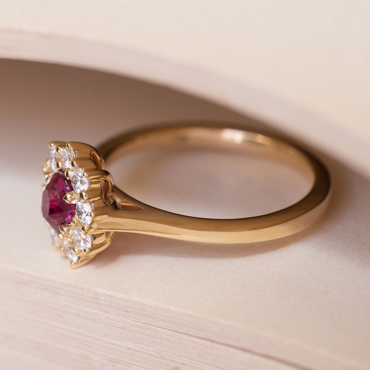 A vintage-inspired pink ruby and diamond cluster engagement ring in yellow gold.