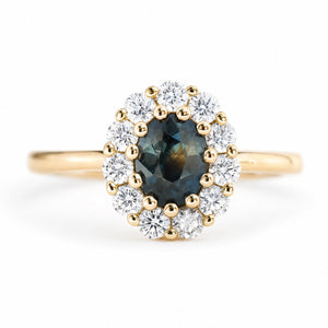 An antique-inspired deep green sapphire and diamond halo cluster engagement ring in 14ct yellow gold.
