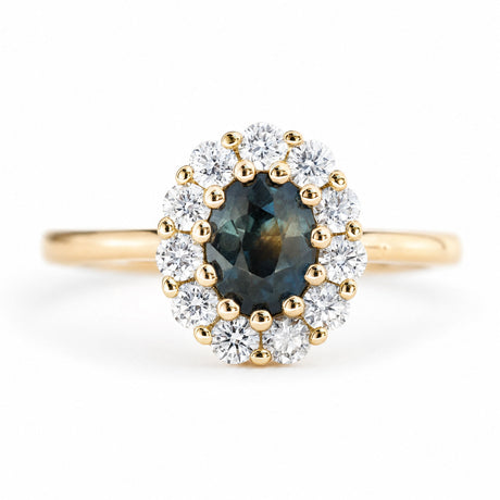 An antique-inspired deep green sapphire and diamond halo cluster engagement ring in 14ct yellow gold.