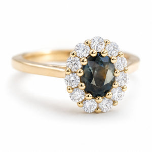 A vintage-inspired yellow gold engagement ring with a deep green sapphire and diamond halo.