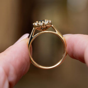 Side profile detail of an antique-inspired deep green sapphire and diamond cluster engagement ring in yellow gold.
