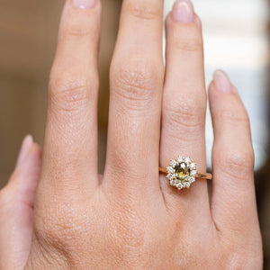 Antique-inspired green sapphire and diamond engagement ring displayed on the hand in yellow gold.