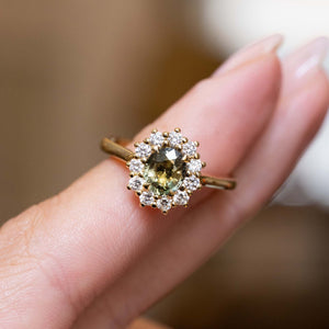 Green sapphire halo cluster engagement ring with diamonds in an antique-inspired yellow gold design.