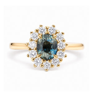 An antique-inspired, teal sapphire and diamond halo cluster engagement ring in yellow gold.