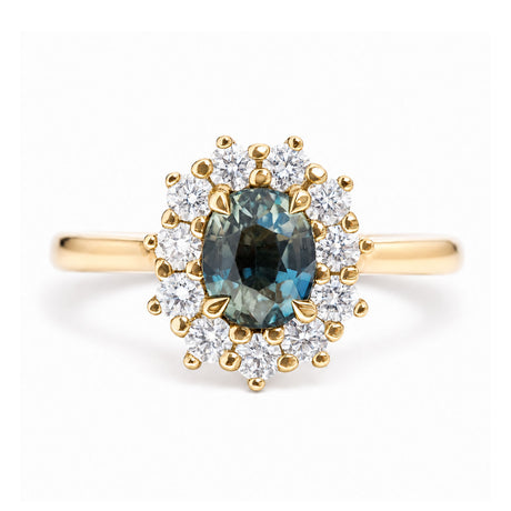 An antique-inspired, teal sapphire and diamond halo cluster engagement ring in yellow gold.
