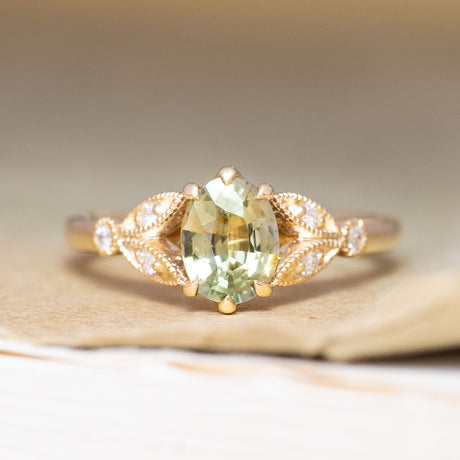 A vintage-inspired, green sapphire & diamond engagement ring in yellow gold.