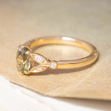An antique-inspired green sapphire and diamond engagement ring, with decorative trefoil shoulders in the form of laurel leaves.