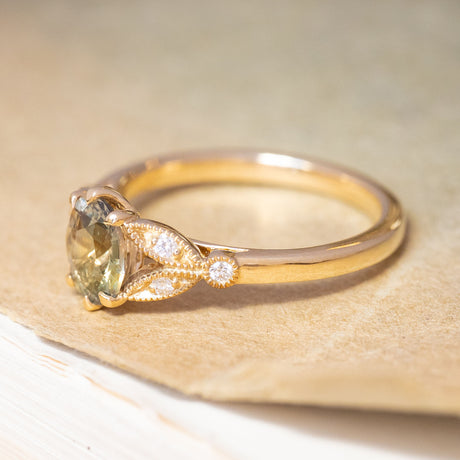 An antique-inspired green sapphire and diamond engagement ring, with decorative trefoil shoulders in the form of laurel leaves.
