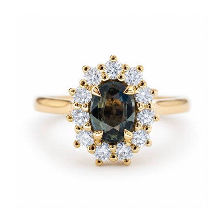 An antique-inspired, green oval sapphire and diamond halo cluster engagement ring in yellow gold. 