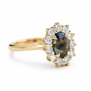 A vintage-inspired yellow gold engagement ring with a green oval sapphire and diamond halo.