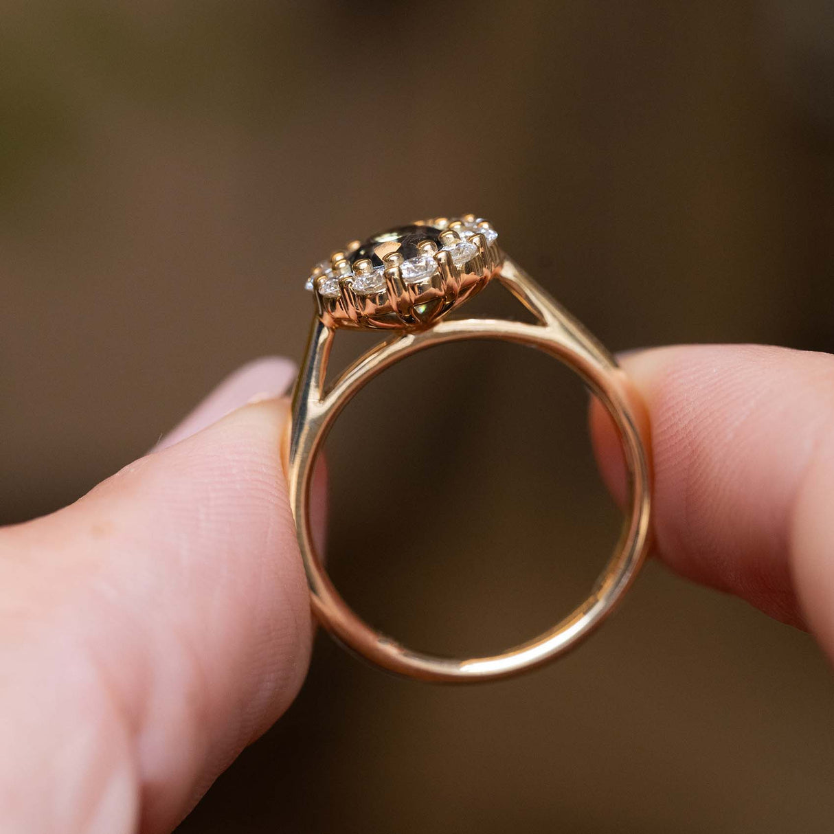 Side detail of an antique-inspired earthy green sapphire and diamond cluster engagement ring in yellow gold.