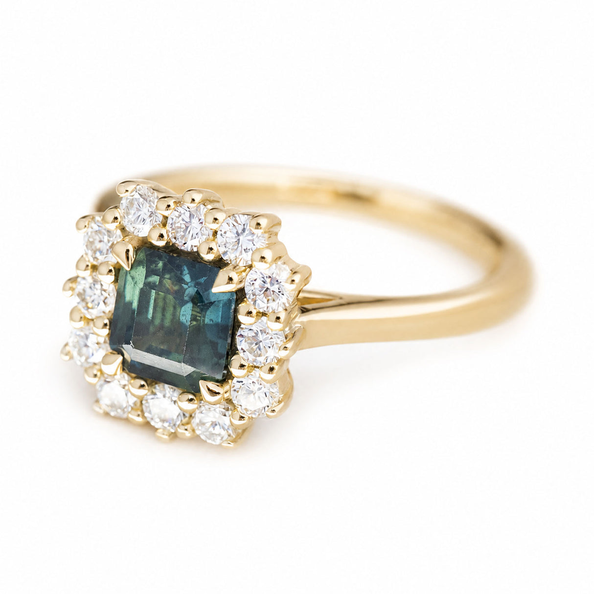 A three-quarter profile of a vintage-inspired, blue-green sapphire and diamond halo cluster engagement ring in yellow gold.