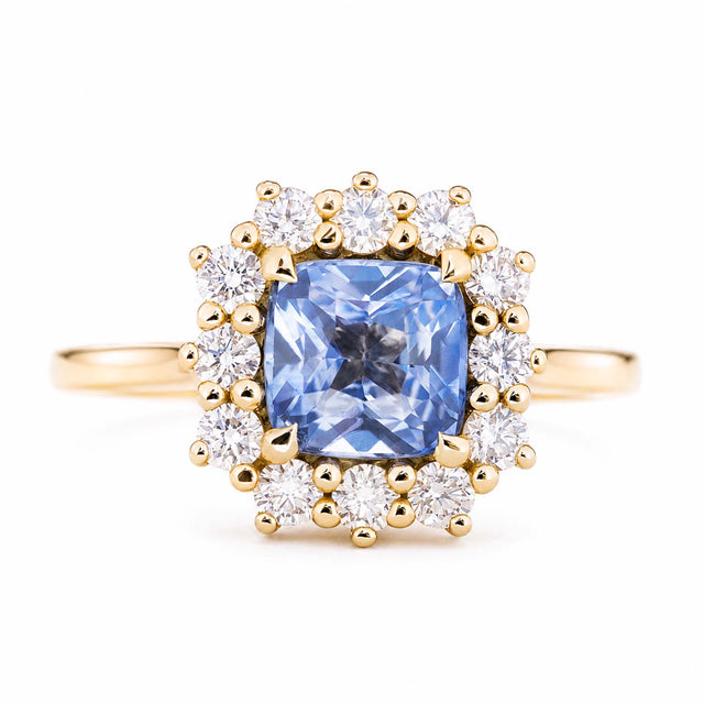 An antique-inspired, blue sapphire and diamond halo cluster engagement ring set in 14ct yellow gold.
