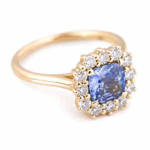 A vintage-inspired yellow gold engagement ring with a blue sapphire and brilliant-cut round diamond halo.