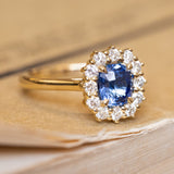 An vintage-inspired, blue sapphire and diamond halo engagement ring in yellow gold. 