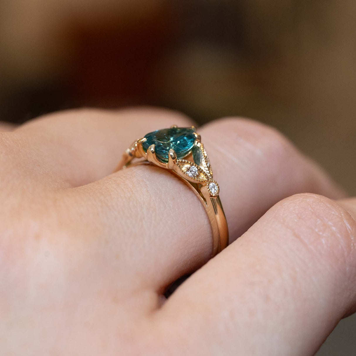 Side view of a pear-cut teal tourmaline ring in yellow gold.