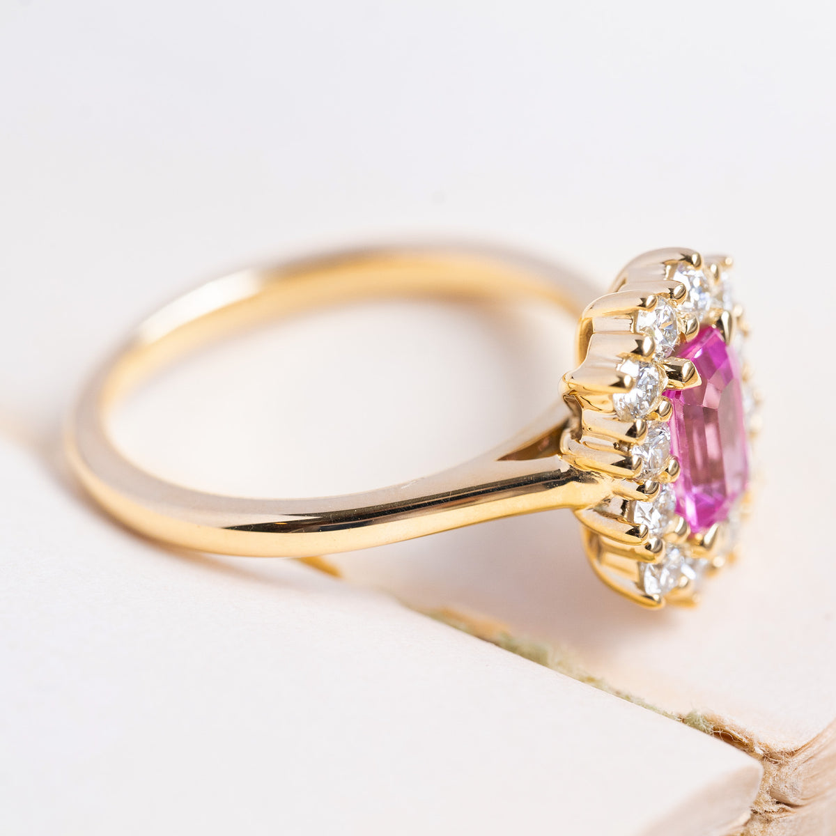 A vintage-inspired, pink sapphire and diamond halo engagement ring in 14ct yellow gold. 