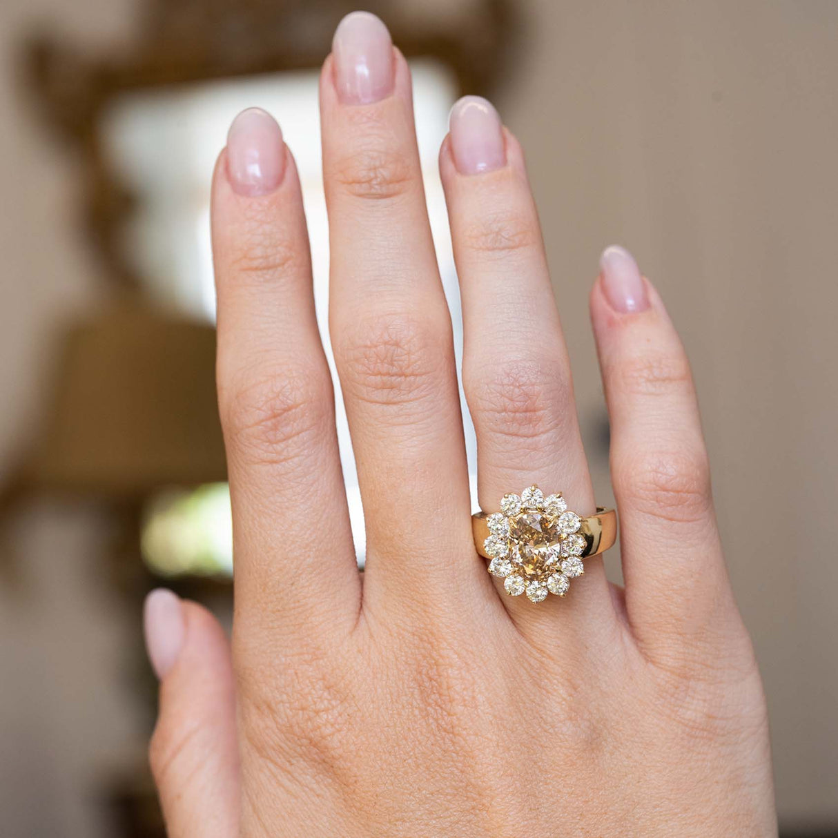 Vintage 1980s fancy coloured brown diamond cluster cocktail ring worn on the hand, featuring an oval brown diamond surrounded by brilliant-cut white diamonds in yellow gold.