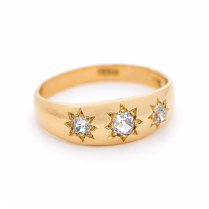 A three-quarter angle of an antique, Edwardian diamond three-stone gypsy ring in yellow gold. 