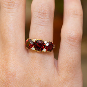 A vintage, 1980s garnet three-stone carved half-hoop ring in yellow gold.