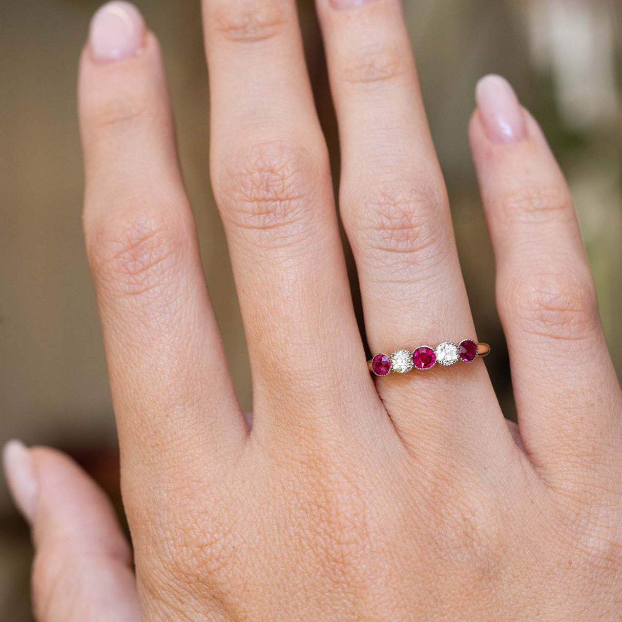 An antique Edwardian ruby and old-cut diamond five-stone ring worn on the hand.