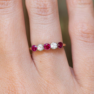 An antique Edwardian ruby and old-cut diamond five-stone ring worn on the finger.