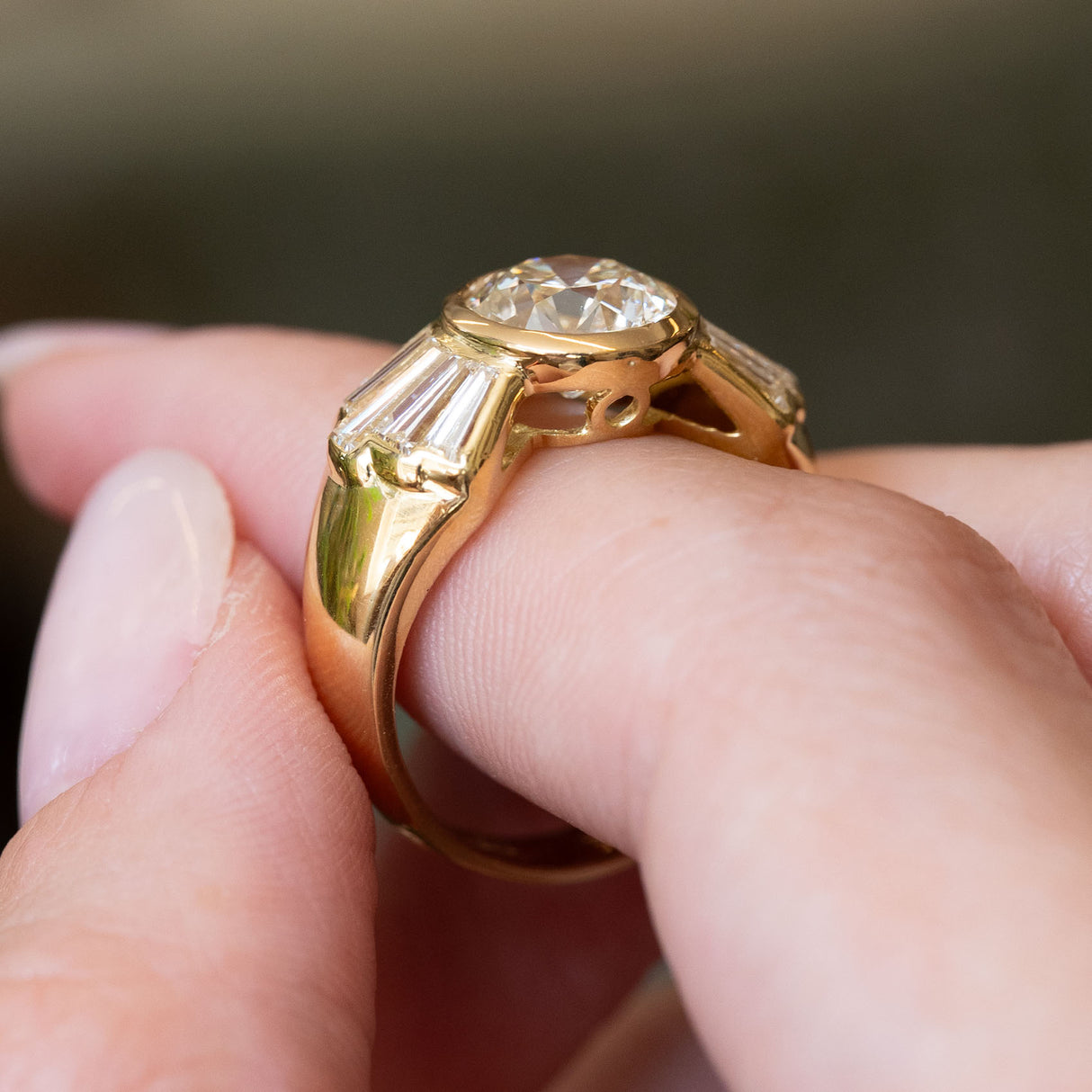 Vintage 1950s diamond engagement ring in yellow gold, highlighting the gallery, setting and tapered baguette diamond shoulders.