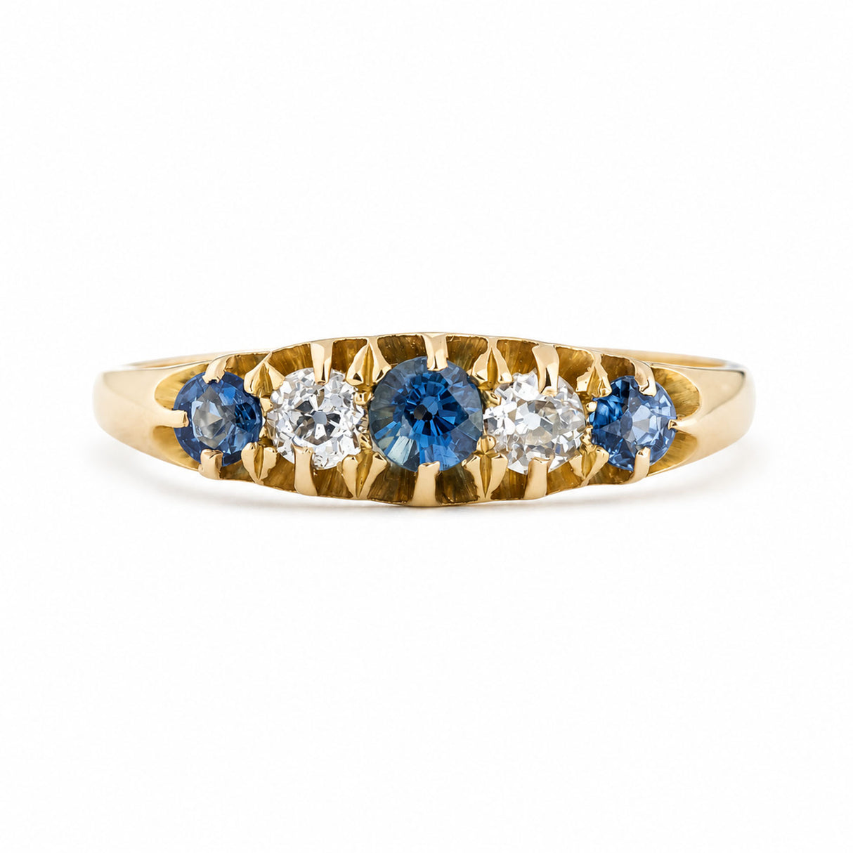 An antique, Edwardian blue sapphire & diamond five-stone ring in yellow gold.
